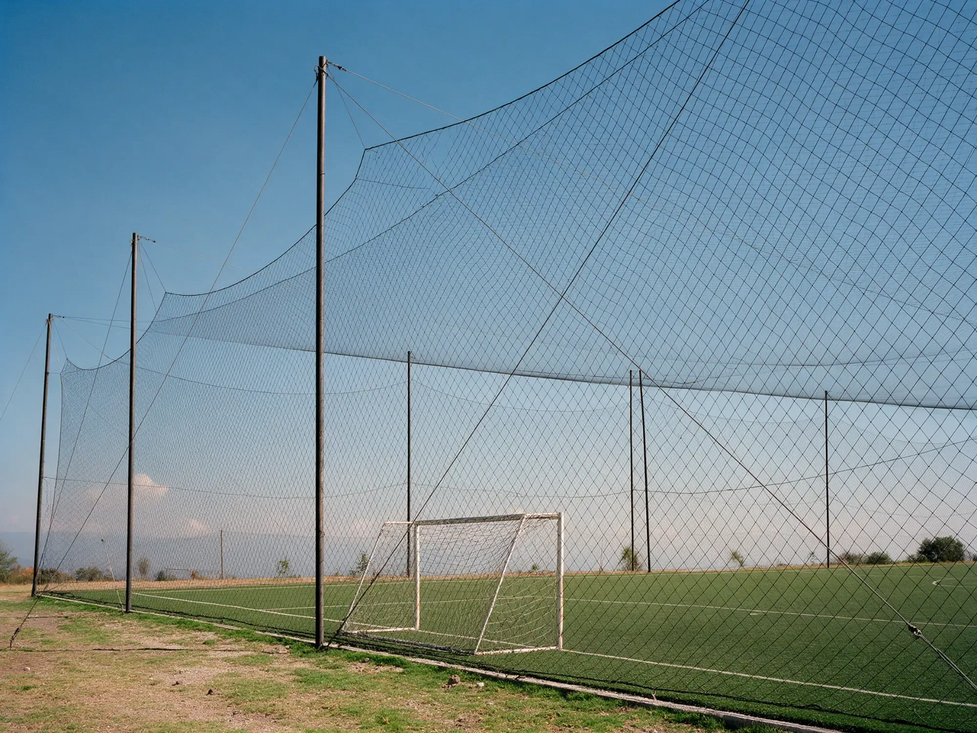 Red perimetral alta alrededor de una cancha de futbol con portería